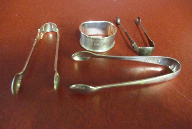 TWO PAIRS OF SILVER SUGAR TONGS WITH SILVER NAPKIN RING AND ANOTHER PAIR OF SUGAR TONGS Image
