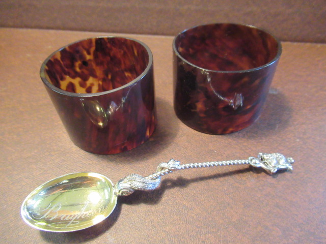 TORTOISESHELL STYLE NAPKIN RINGS AND A SILVER SPOON Image