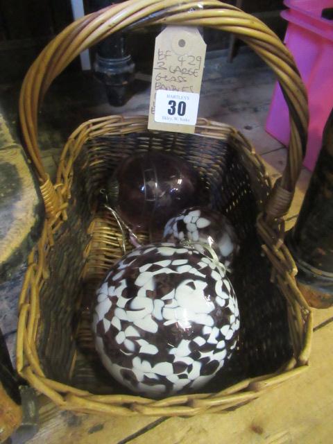THREE LARGE GLASS BAUBLES IN A WICKER BASKET Image