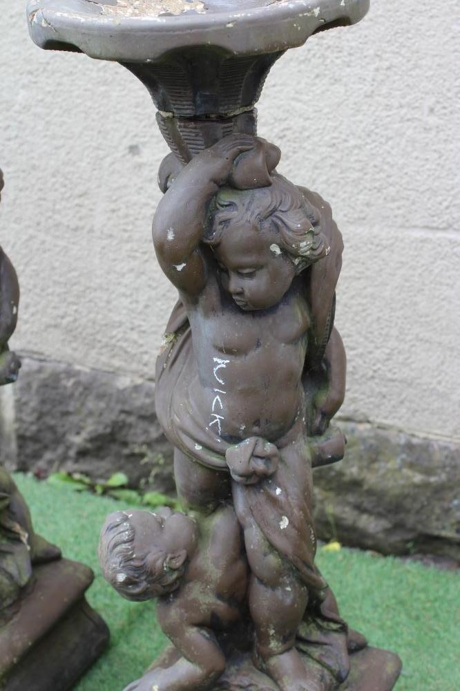 PAIR OF CONCRETE FIGURAL BIRD BATHS each with two cavorting cherubs supporting a shallow bowl, on Image