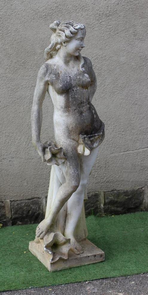 A CAST STONE FIGURE OF A WATER NYMPH, the nude figure standing and holding a shell, another shell at Image